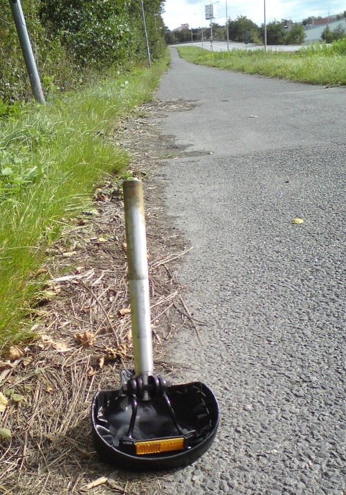 En cykelsadel med sadelstolpe,kvarglömd på cykelbanan